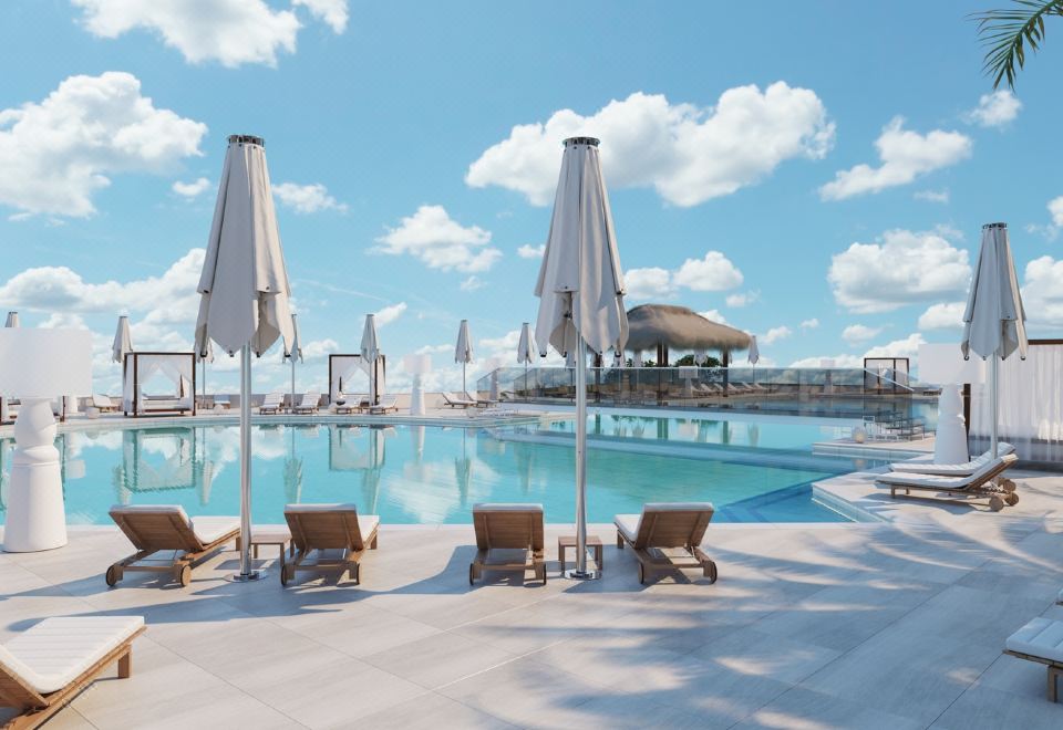 a large outdoor pool surrounded by lounge chairs and umbrellas , providing a relaxing atmosphere for guests at Iberostar Selection Creta Marine