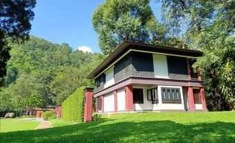 a house with a red roof and white walls is surrounded by green grass and trees at Lanna Resort Chiang Mai