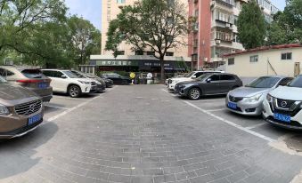 A photo taken from the parking lot shows multiple cars parked in front of an entrance at Jinjiang Inn (Beijing Anzhenli)