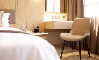 A hotel or motel-style bedroom area with a bed, desk, and chair at B P International