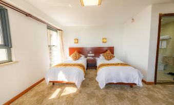 The bedroom features double beds and large windows, all within a living space with white walls at Guangmingding Hotel