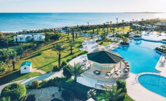 a resort with a pool , a bar , and a gazebo surrounded by palm trees and grass at Iberostar Selection Royal El Mansour