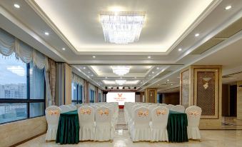 a long dining room with white chairs and green tablecloths , set up for a formal event at Vienna Hotel