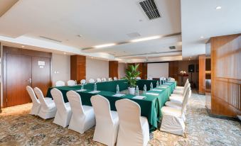 a conference room with a long table covered in green tablecloth , surrounded by white chairs at Como Hotel