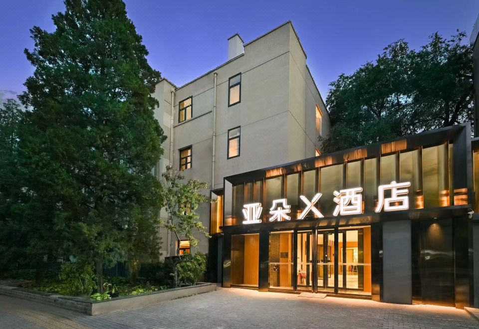 The hotel's front entrance features a glass and steel door with an illuminated sign above it at X Hotel Taikoo Riaduo, Sanlitun, Beijing