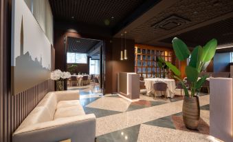 a modern lounge area with white couches , wooden tables , and chairs , as well as a dining table and a vase at Hotel Minerva
