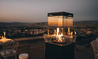 a rooftop dining area with a fire pit surrounded by chairs , tables , and a view of the city at Museum Hotel - Special Class