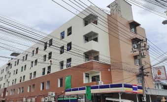 a brick building with multiple floors , located on a busy street in a residential area at Kim Hotel at Bangplong