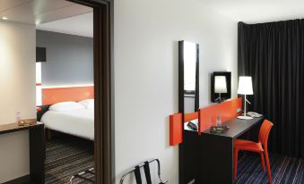 a modern hotel room with a black and white theme , featuring an orange chair , desk , bed , and lamp at Ibis Styles Caen Centre Gare