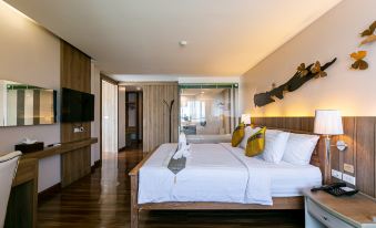 a large bed with white linens and a wooden headboard is in a room with hardwood floors at Grand Ratchapruek Hotel