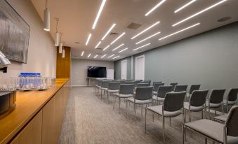 a conference room with rows of chairs arranged in a semicircle , and a television mounted on the wall at Radisson Beach Resort Larnaca