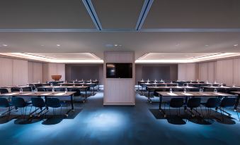 In a spacious room, rows of tables are arranged in front, while the back wall remains empty at Novotel Shanghai Hongqiao Gubei