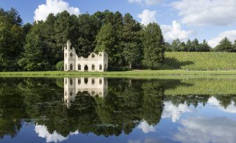 a serene lake surrounded by lush green trees , with a building situated on the shore at Hilton Cobham