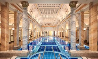 a large indoor swimming pool with marble walls and columns , surrounded by pillars and tiled floors at Grand Resort Bad Ragaz