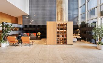 The living room features couches and chairs arranged in the center, adjacent to an open concept at base SUHE Serviced Apartment