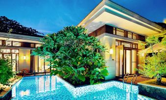 a modern villa with a swimming pool , surrounded by lush greenery and tropical plants , at night at Sanya Haitang Bay Island Villa (International Duty Free City Branch)
