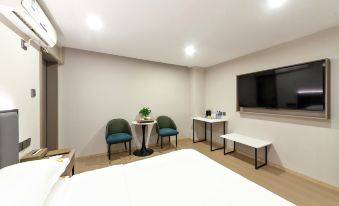 a hotel room with a bed , two chairs , and a tv mounted on the wall at Diamond Hotel (Liancheng Guanzhishan Airport)