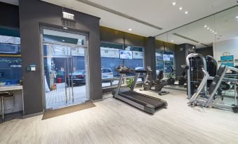The room is spacious and equipped with multiple exercise machines, with an indoor water park visible in the background at Jinjiang Inn (Shanghai People's Square East Huaihai Road)