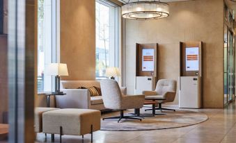 a modern waiting area with beige furniture , large windows , and a chandelier , decorated in neutral colors at Lotte City Hotel Ulsan