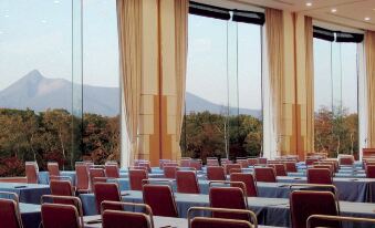 a large conference room with rows of chairs arranged in front of a long table , overlooking a beautiful mountain view at Hakodate-Onuma Prince Hotel