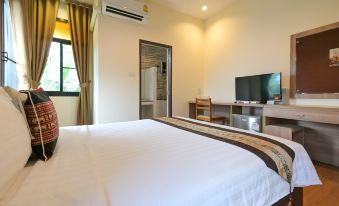 a clean , well - organized bedroom with a large bed and a flat - screen tv mounted on the wall at Baan Kieng Tawan