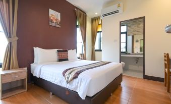 a large bed with white linens is situated in a room with wooden floors and a brown wall at Baan Kieng Tawan