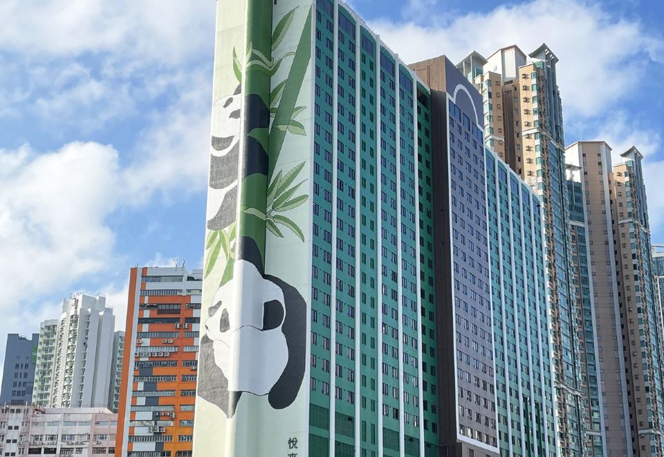 "A large building with a sign that says ""hotel"" on its side and another sign expressing affection" at Panda Hotel