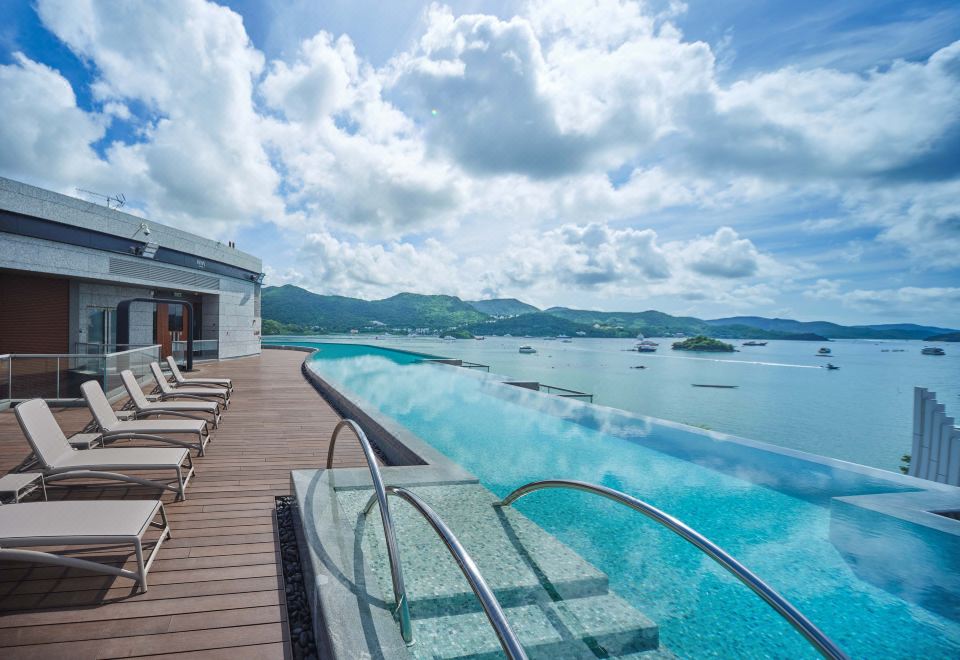 The modern hotel features a large swimming pool with an ocean view, providing a scenic overlook of the water and beach at WM HOTEL HONG KONG, Vignette Collection