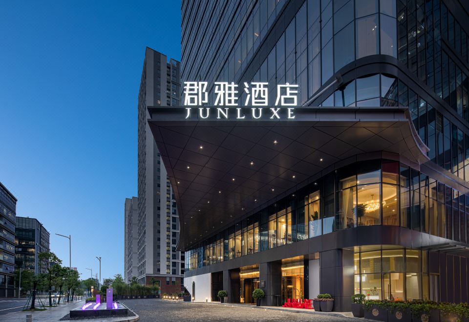 The front entrance of a hotel is located in an urban setting, surrounded by tall glass and steel buildings at Junluxe Guangzhou Baiyun