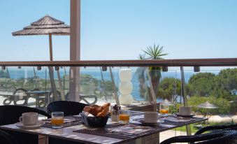 a dining table set with a variety of food and beverages , including coffee , oranges , and croissants at Vila Alba Resort