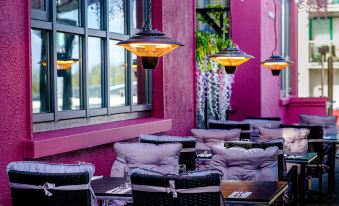 an outdoor dining area with purple walls , tables , and chairs , as well as potted plants and umbrellas at Claregalway Hotel