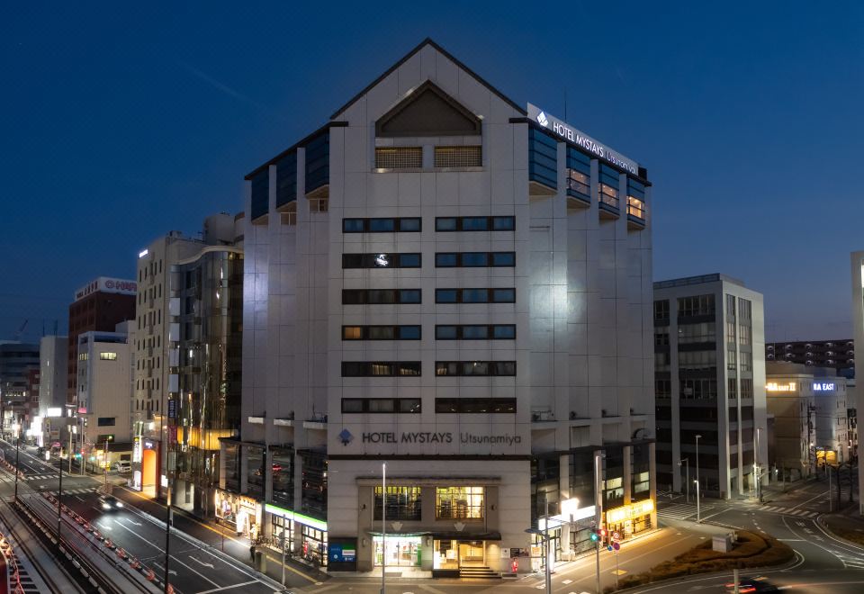 a large white building with a hotel sign on the top floor , located in a city at night at HOTEL MYSTAYS Utsunomiya