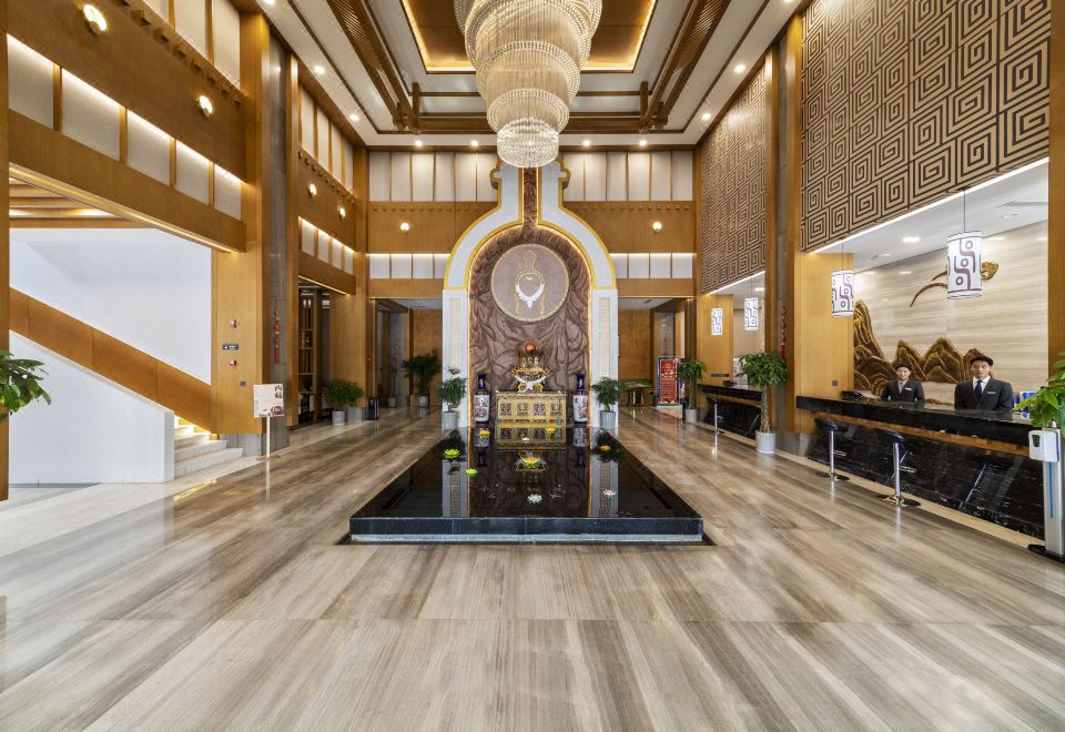 a large hotel lobby with a fountain in the center , surrounded by chairs and tables at Tibet Hotel