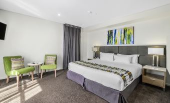 a modern hotel room with a large bed , a chair , and a painting on the wall at Metro Hotel Perth