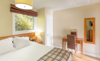 a hotel room with a bed , desk , and chair , as well as a window overlooking the outdoors at Pine Lake Resort