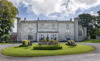 a large stone building with a fountain in front of it , surrounded by a grassy area at Thurnham Hall