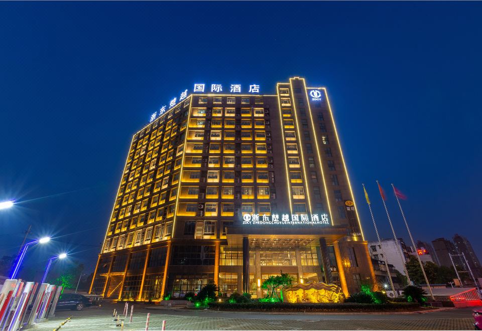 The building housing a hotel is illuminated with neon lights during the night at Zhedong Chuyue International Hotel