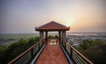 a red - tiled patio with a wooden deck , surrounded by lush greenery and overlooking a beautiful landscape at Victoria Nui Sam Lodge