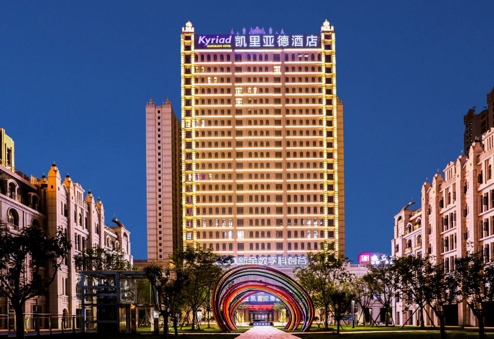 At night, there is a large illuminated building surrounded by other buildings at Kyriad Marvelous Hotel (Xinyu Jiuding Kongmujiang Store)