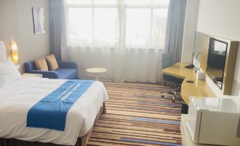 a hotel room with a blue bed , desk , and window , along with a bed and desk at Holiday Inn Express