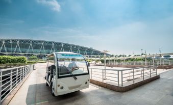 A small vehicle is parked on the sidewalk next to another car in front, along with other vehicles at Novotel Guangzhou Baiyun Airport (Terminal)