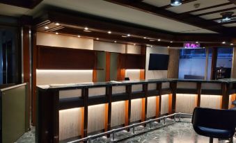 a modern office reception area with a long counter , several chairs , and a tv mounted on the wall at Savoy Hotel