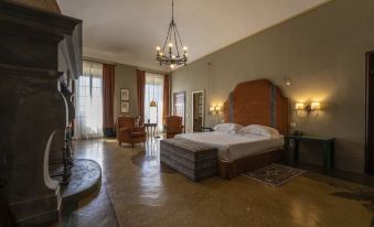 a large bedroom with a bed , two chairs , and a fireplace in the background , all decorated in neutral colors at Palazzo Leopoldo Dimora Storica & Spa