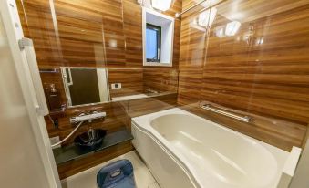 The bathroom features wood paneling and white tile walls, with a bathtub adjacent to it at Yadoya Fukurou