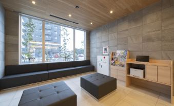 a modern room with a large window and wooden ceiling , featuring a black bench , storage shelves , and a small table at Just Inn Matsusaka Station
