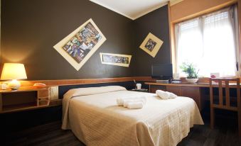 a bedroom with a bed , two pictures on the wall , and a window with a plant at Hotel Diplomatic