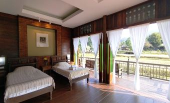 a bedroom with two beds , one on each side of the room , and a sliding glass door leading to a balcony at Lhongkhao Samoeng by Chi Villa