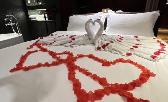 a bed with red rose petals arranged in the shape of a heart , creating a romantic atmosphere at M Hotels