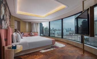 The bedroom features large windows and a balcony with a city view, but the bed is unmade at Blossom House Shanghai On The Bund