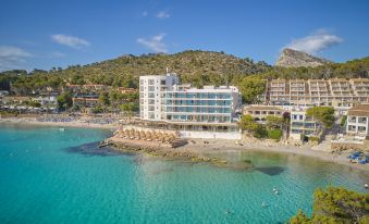a modern hotel building situated on the shore of a beautiful blue sea , with clear blue water and clear skies at Universal Hotel Aquamarin